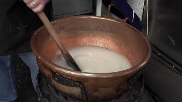 candy making stirring sugar in copper kettle