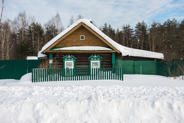 Typical old wooden house covered with snow in the Russian village/ Winter Landscape/ Russia
