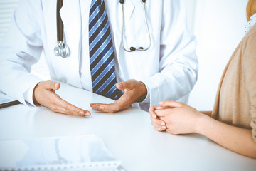 Doctor and patient woman discussing something at the desk in hospital office. Concepts of medical ethics and helping people in medicine