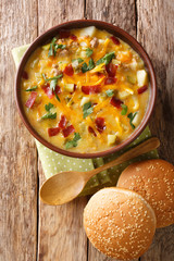 Tasty cheeseburger soup with vegetables, ground beef, cheese and bacon close-up in a bowl. Vertica ltop view
