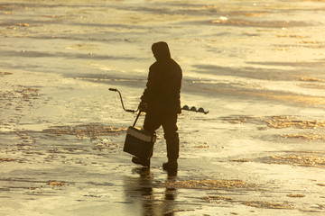A fisherman catches fish on ice at dawn