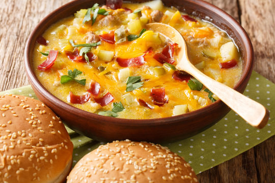 cheeseburger soup topped with bacon and cheddar cheese close-up in a bowl on the table. horizontal