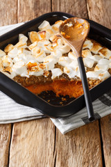 Festive sweet potato dessert with pecans and marshmallows close-up in a baking dish. vertical