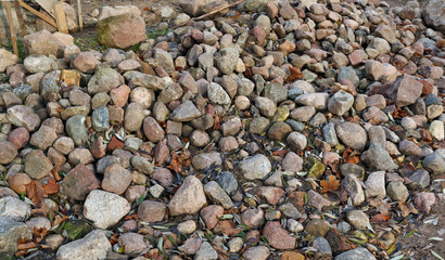 A large pile of small granite cobble stones for the construction of a rural shed   or barn