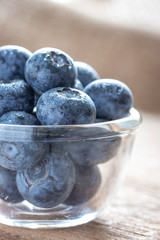 Blueberries in a glass bowl on wooden table and texture, fresh fruit with water droplet