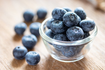 Blueberries in a glass bowl on wooden table and texture, fresh fruit with water droplet