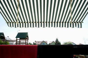 striped awning above the terrace of the holiday house - obrazy, fototapety, plakaty