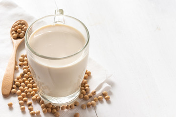 Soy or soya milk in a glass with soybeans background
