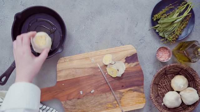 Time lapse. Flat lay. Preparing garlic spread by roasting garlic with fresh spices in cast iron frying pan.