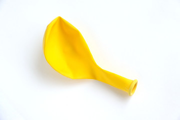 Deflated yellow balloon isolated on a white background