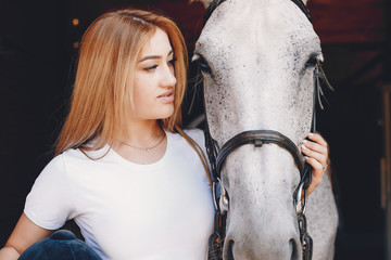Cute girl with a horse. Lady in a white t-shirt. Woman in a summer park