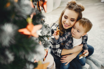 Beautiful family sitting near Christmas tree. Cute mother in a blue shirt