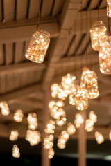 Jars hanging from the ceiling of the bar with warm led lights inside.
