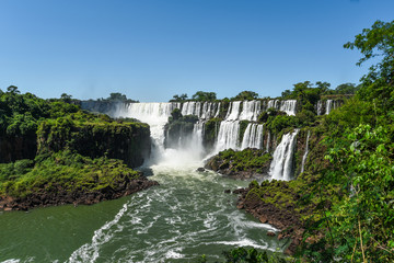 Fototapeta na wymiar Famous Iguazu waterfalls with beautiful clouds. Declared a World heritage and one of the seven Natural Wonders of the World Brasil Argentina. Iguazu National Park
