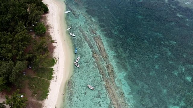 4K Drone Aerial Shot along beach coastline with anchored Boats Over Clear Blue Water