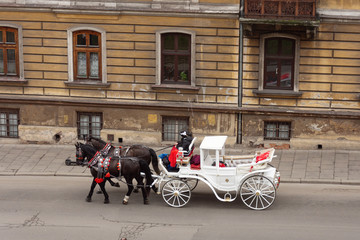 Horse carriage on the street of the old town in Krakow, Poland. Two horses in old-fashioned coach, entertainment for tourists excursion.