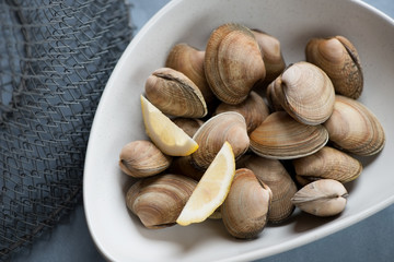 Grey bowl with raw uncooked vongole clams, high angle view, close-up