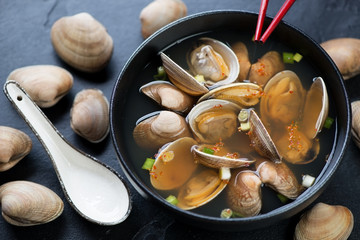 Vongole miso soup served in a black bowl, selective focus, studio shot