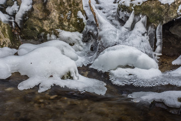 schneehauben bei einem wildbach im winter