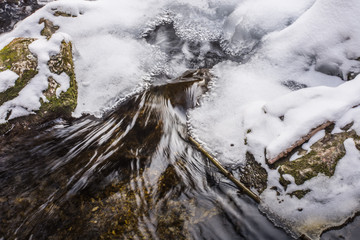 stroemendes wasser mit eis und schnee in einem wildbach