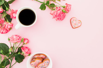 Breakfast composition with roses flowers, cookies and cup of coffee on pink background. Flat lay