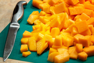 Yellow pumpkin sliced in small cubes for cooking lies on the table