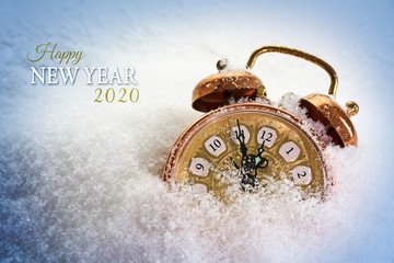 Happy New Year 2020 text and a vintage alarm clock in the snow shows five minutes before twelve, concept greeting card with copy space