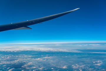 Fototapeta premium At sunrise wing of an airplane flying above the clouds