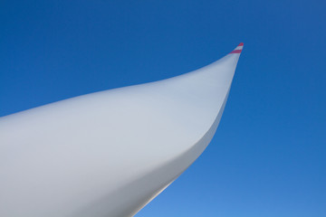 Detail of a large rotor blade of a wind turbine against a blue sky in the background