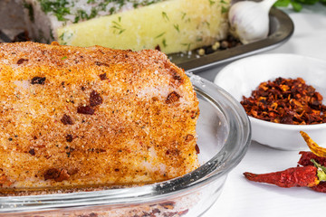 A large piece of salted lard with paprika and hot pepper lies in an oval glass bowl