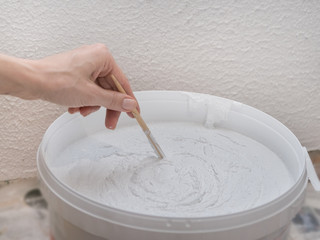 Worker mixes construction putty in a bucket.