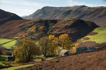 Old derelict farm buildings in Autumn Fall landscape image in Lake District with Sleet Fell in background with epic light on the fells