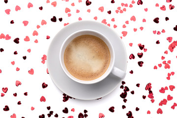 Red sparkles confetti in heart shape and cup of coffee on white background