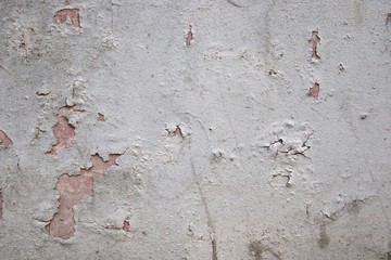 Rough cracked wall with peeling gray paint. Facade texture