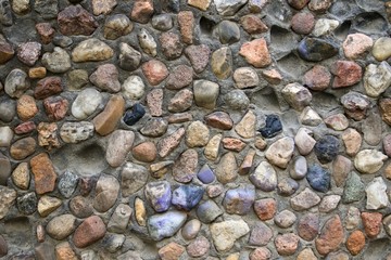 Facade of a concrete building with stones. Multi-colored stones