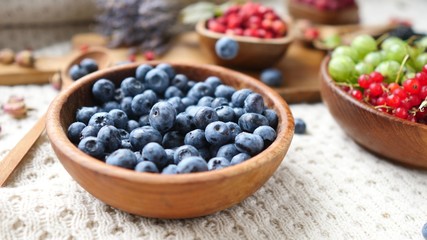 Closeup Of Falling Blueberry In Wooden Bowl On Table.