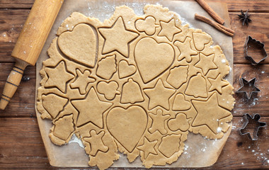 Gingerbread cookie dough with cut out figures on wooden background