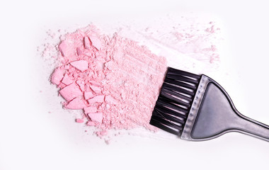 a crumb of pink highlighter powder and a black hair dye brush on a light background, top view
