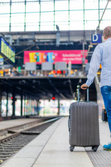 Mann mit Koffer wartet auf den Zug/Bahn im Hamburger Hauptbahnhof