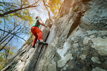Fototapeta premium A free aged male climber hangs on a rock wall in a forest in the mountains. Mature Sports Concept