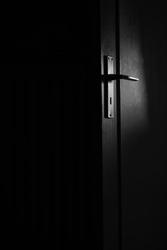 Mondschein beleuchtet leicht die T&uuml;r mit T&uuml;rklinke den dunklen Raum