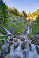 Wasserfall in mitten eines steinigen Pfades im Wald beim Sonnenuntergang