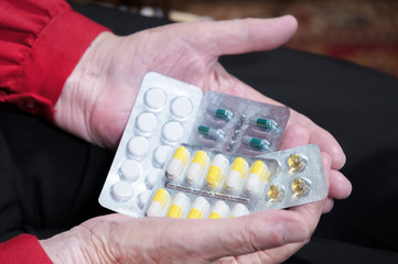 Closeup of a tablet on the hands of an old woman. The concept of choosing medication in old age