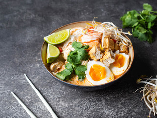 Malaysian noodles laksa soup with chicken, prawn and tofu in a bowl
