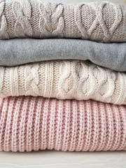 Stack of warm knitted woolen sweaters pastel shades