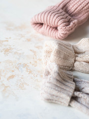 Sleeves of three of warm different knitted woolen sweaters pastel shades beige textured background.