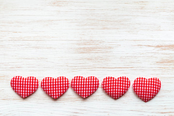 Fototapeta premium Valentine's Day concept. Valentines day background with line of red textile hearts on wooden planks.
