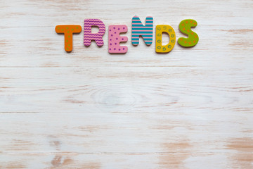 Word trend of colorful wooden letters on vintage white painted wood background. Top view, copy space. Trend concept.