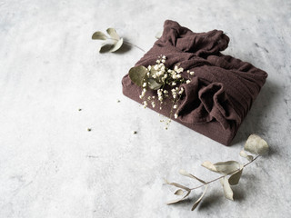 Eco-friendly fabric reusable gift packaging with Eucalyptus and white flowers. Romantic reusable sustainable gift wrapping alternative. Zero waste concept.