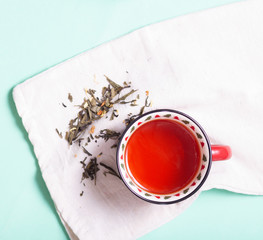 brewed black tea in a mug on a cotton napkin on a light background, top view